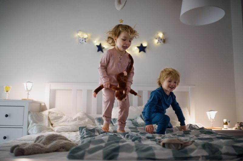  two toddlers jumping on top of a bed