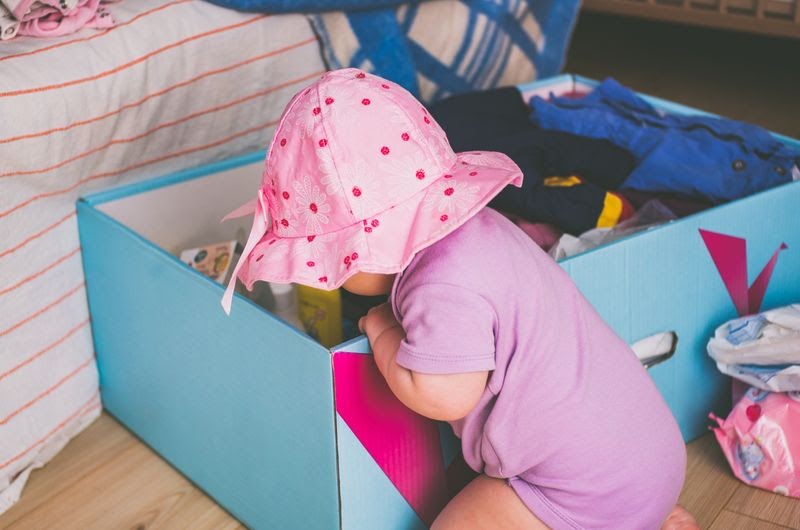 child wearing pink and rummaging a blue box